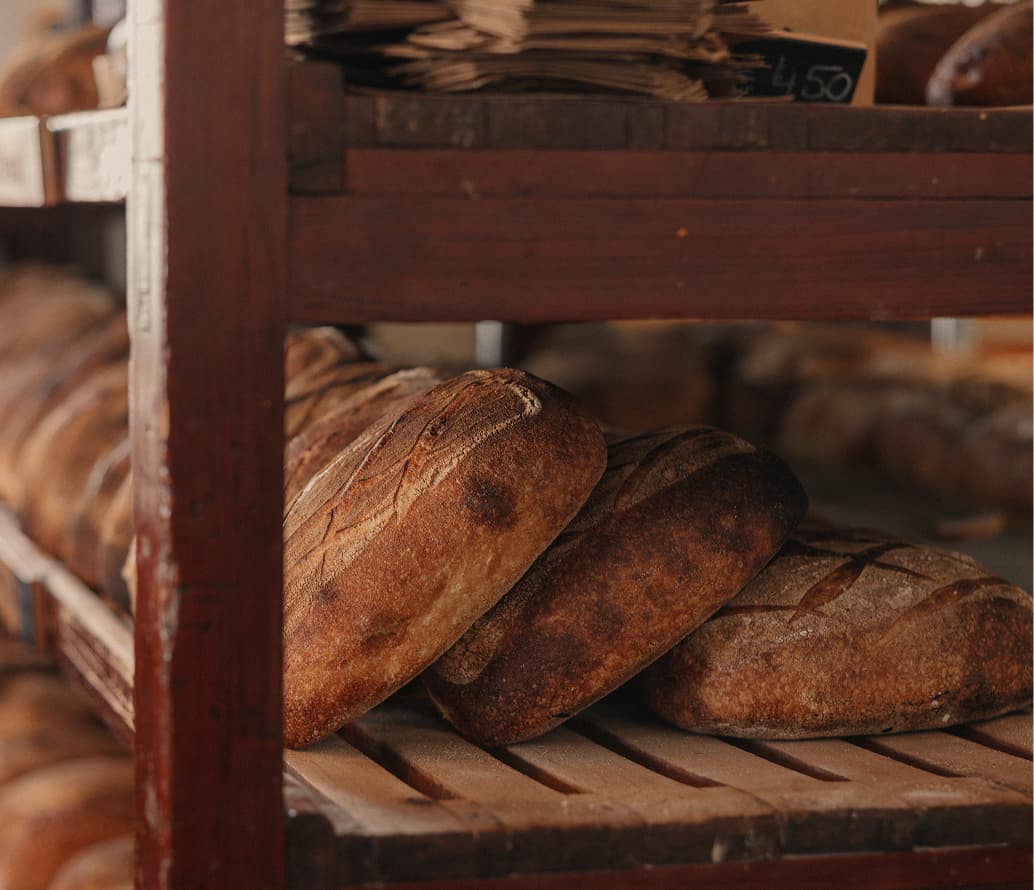 Loaves of freshly baked bread cooling on wooden shelves