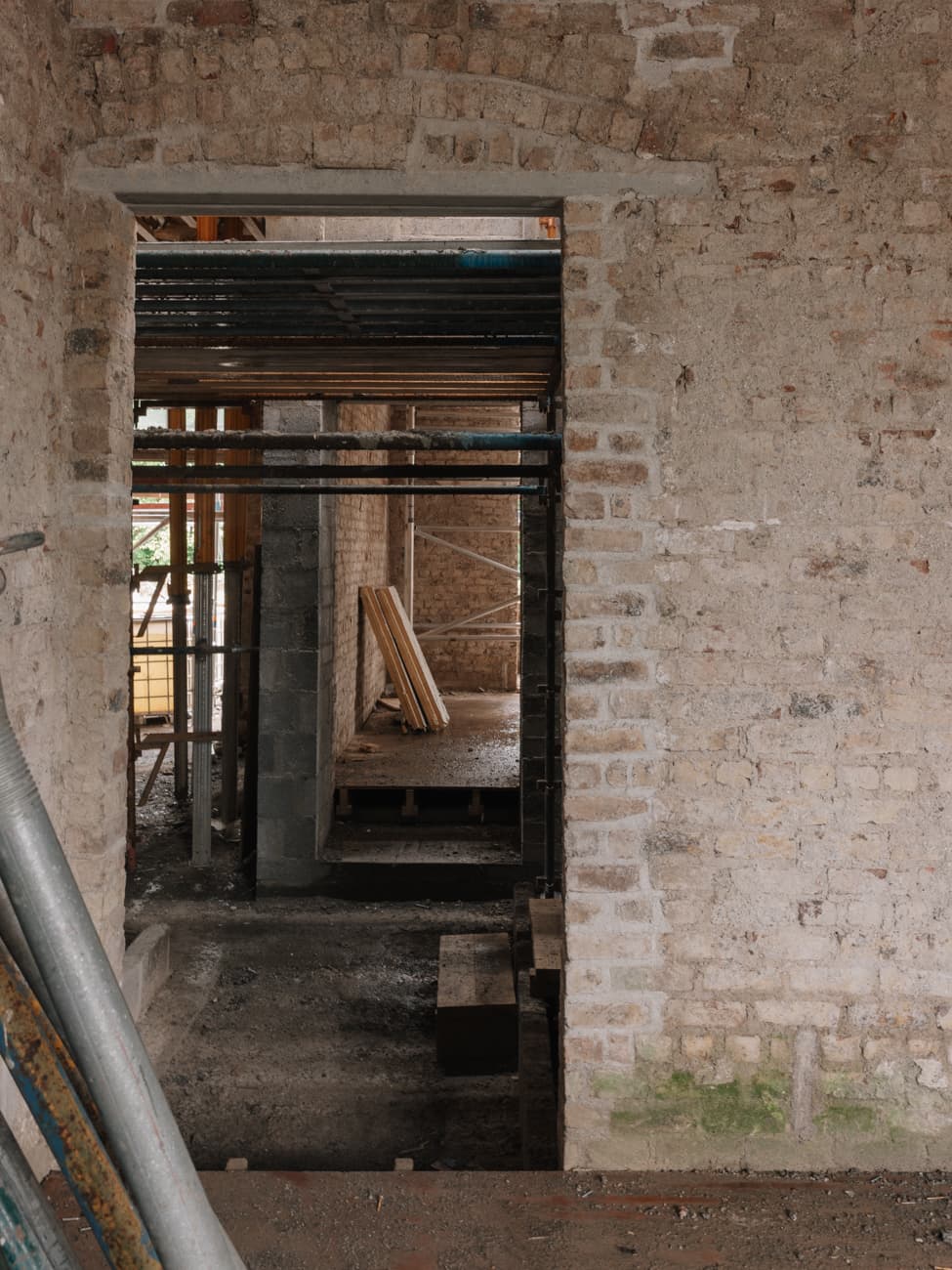 Interior during renovation with exposed stone walls and steel beams